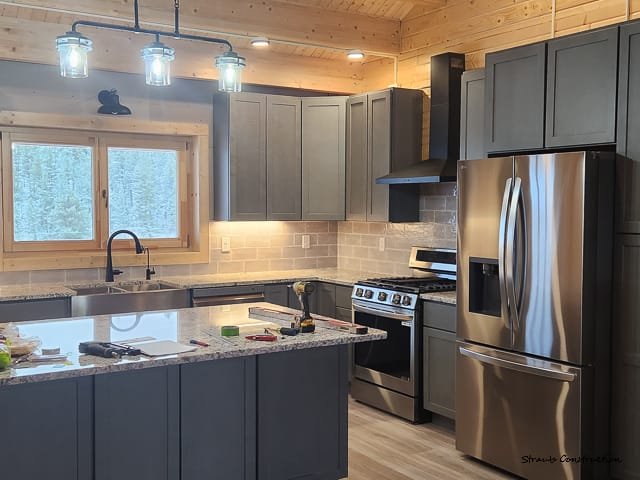 Kitchen cabinets, backsplash tile, lighting fixtures, countertops, appliances installation and wood trim in new home build in Glacier View Meadows near Red Feather Lakes, Colorado