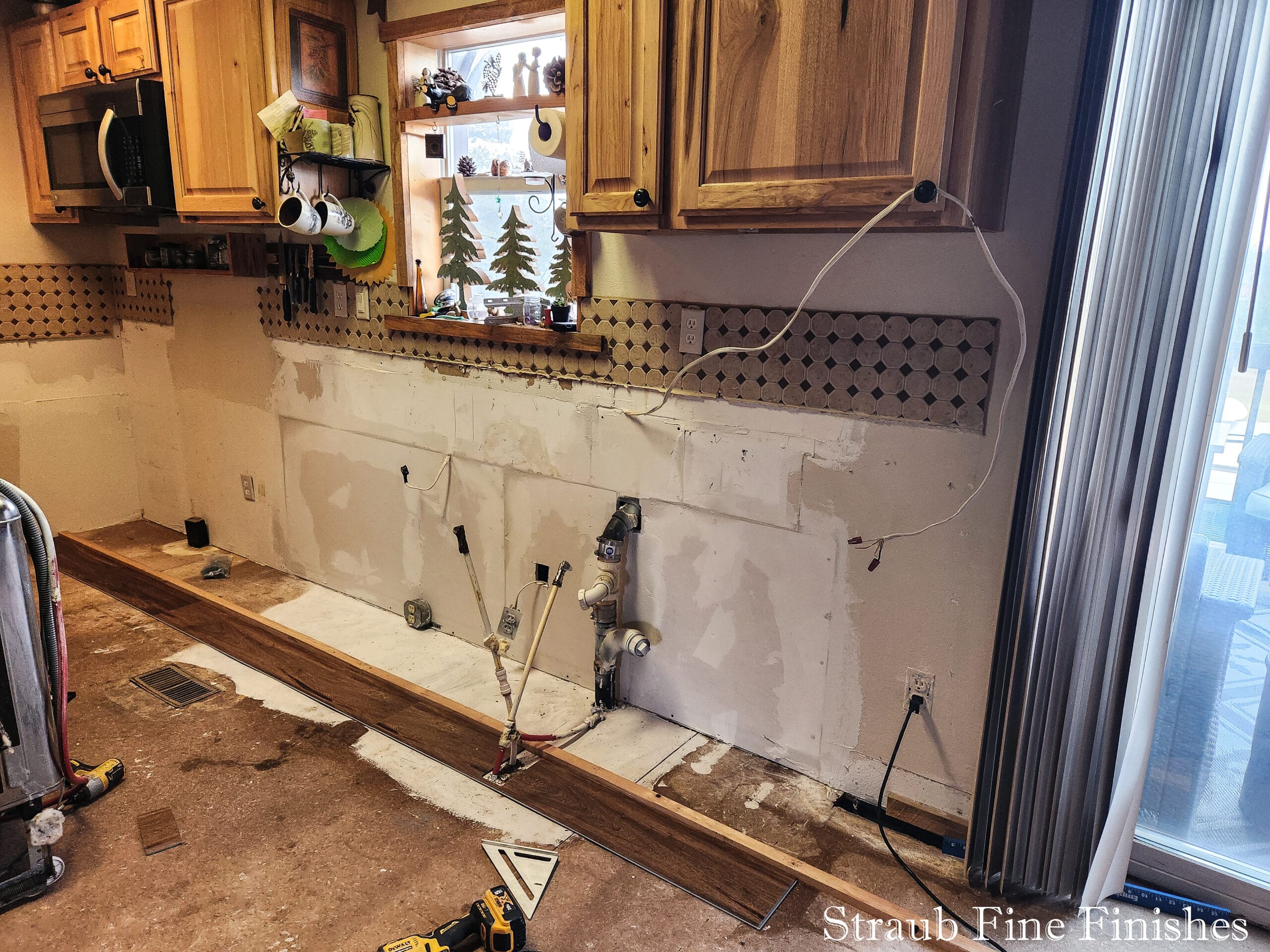 Straub Fine Finishes made the required plumbing repairs, and added studs, drywall and insulation behind the original kitchen cabinets. The kitchen was originally built without an interior wall, we could see straight through to the back yard.