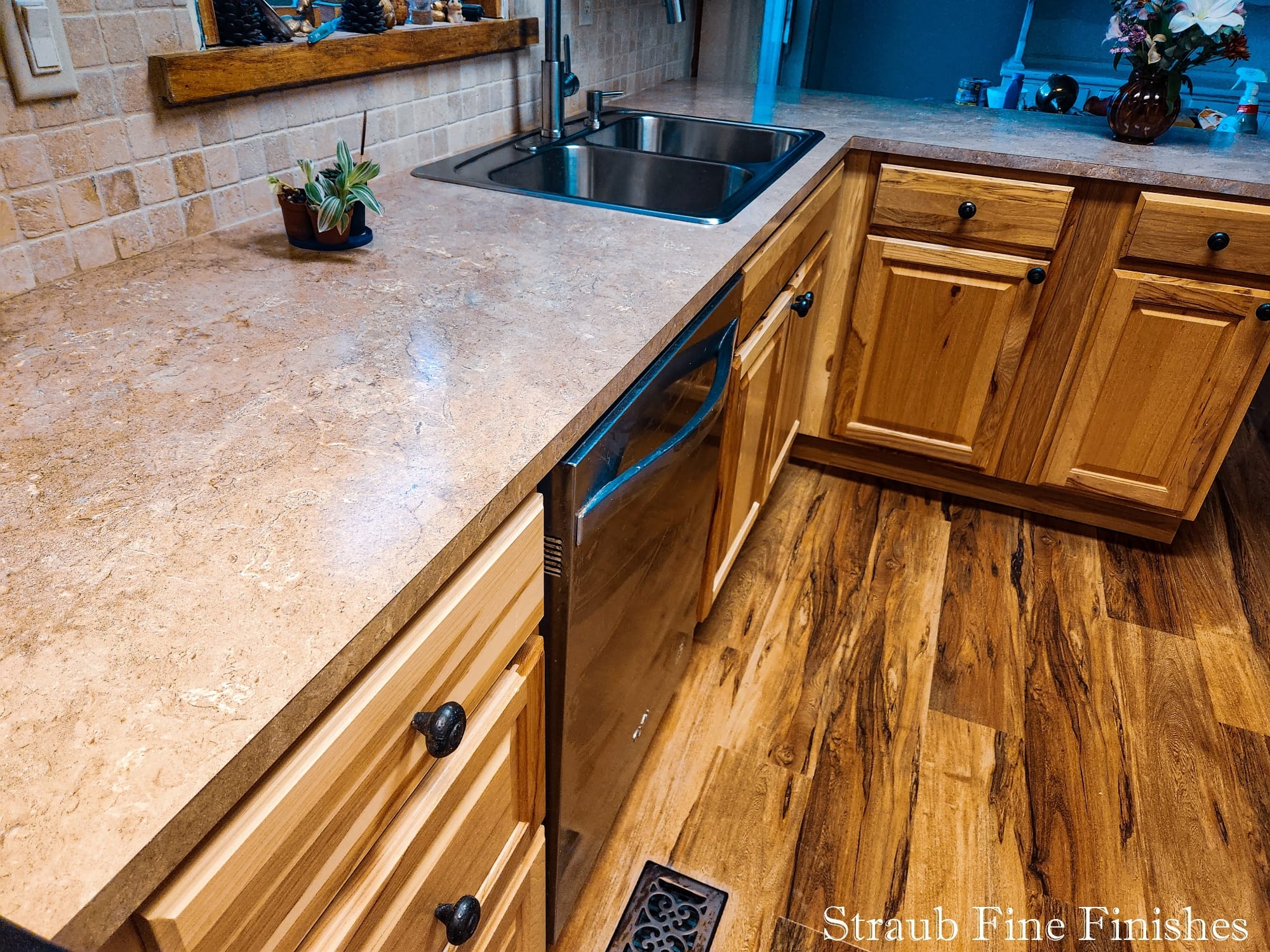 Cabin kitchen with hickory cabinets, a tumbled-stone backsplash, and solid-surface countertops by Straub Fine Finishes