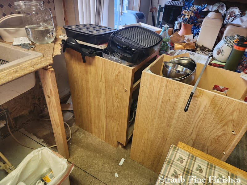 Kitchen mid-restoration with cabinets removed and the subfloor exposed during an insurance repair by Straub Fine Finishes