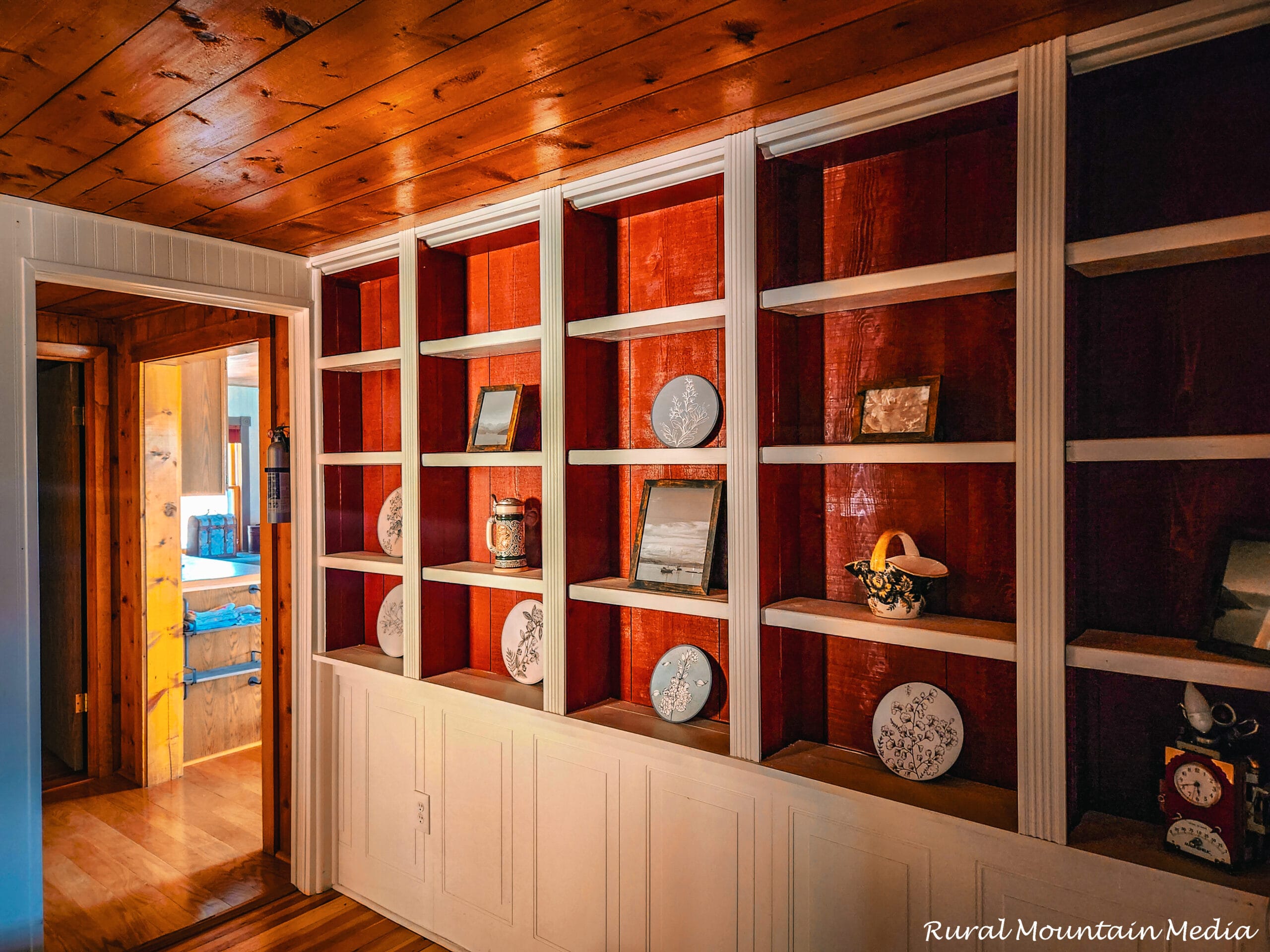 Custom built-in bookshelves with cedar backing and white trim in a restored 1897 cabin