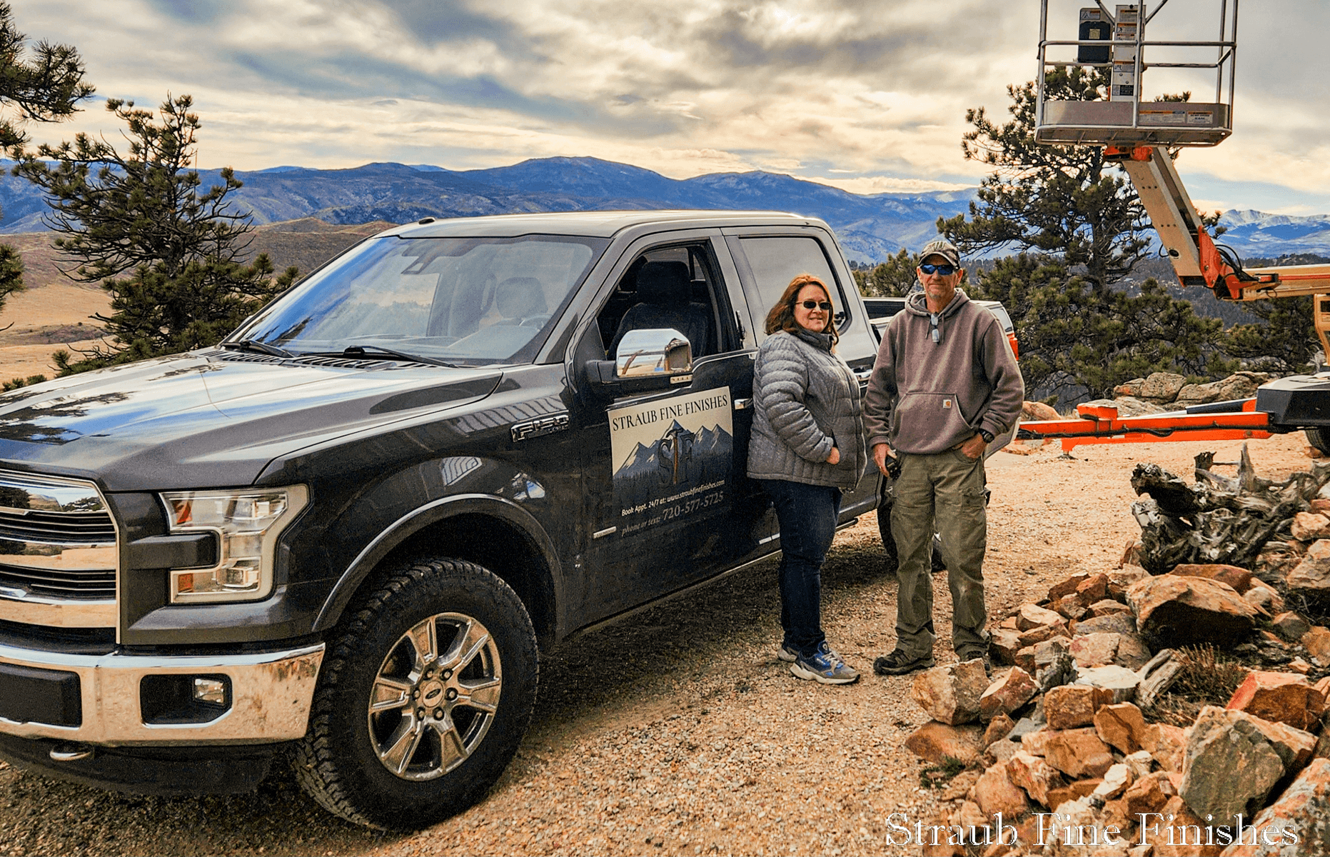 Chris and Faye Straub on a mountain job site beside their Straub Fine Finishes truck and lift equipment